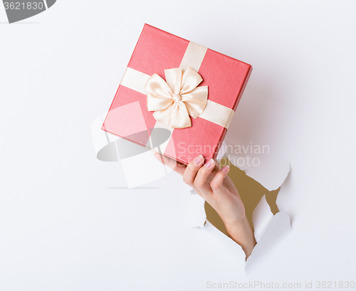 Image of Hand hold with gift box through the white paper