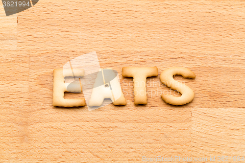 Image of Word eats biscuit over the wooden background