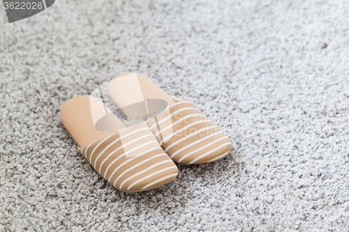 Image of Pair of white slippers on a carpet