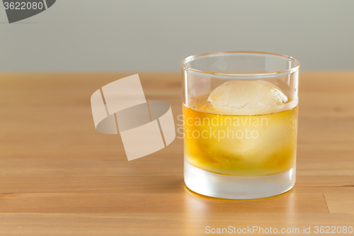 Image of Whiskey drink on wood with ice cube