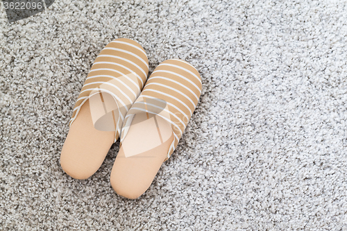 Image of Soft brown color slippers on carpet 