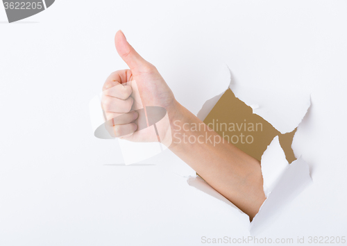 Image of Hand break through paper with thumb up sign