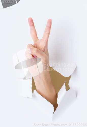 Image of Woman hand breaking through paper wall pointing with the two fin