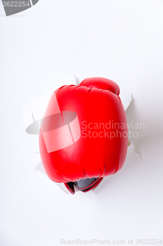 Image of Hand in boxing glove through paper hole