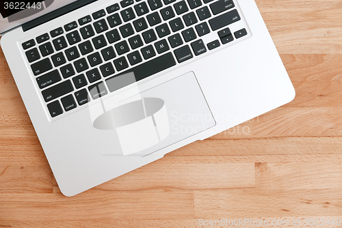 Image of Laptop computer on a wooden desk. Top view