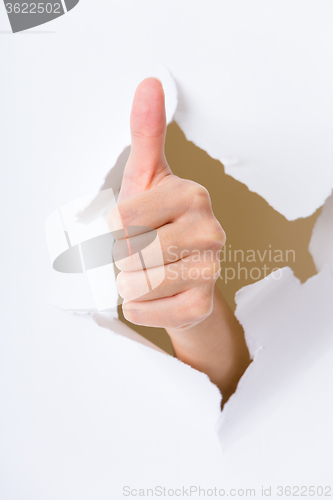 Image of Thumb up hand gesture break through the paper wall