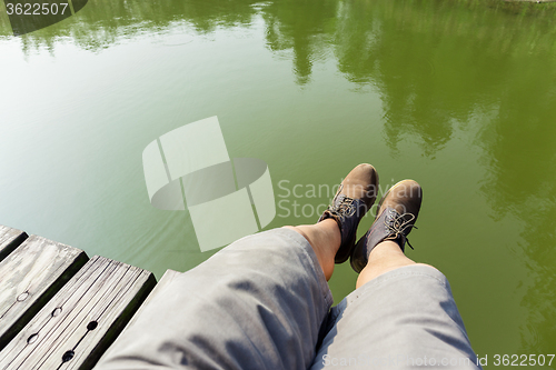 Image of Man legs sitting on wooden path