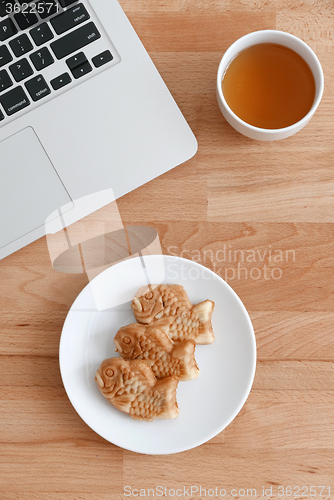 Image of Laptop computer with japanese fished shaped cake and tea