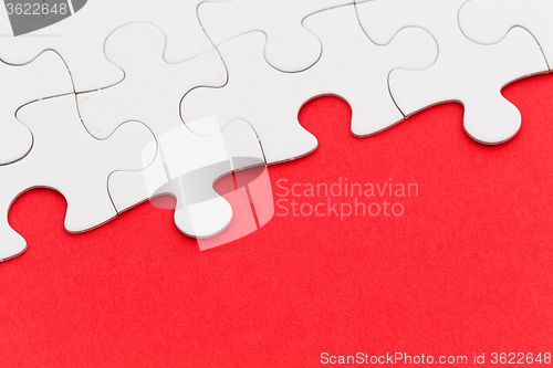 Image of White paper jigsaw puzzles over red background