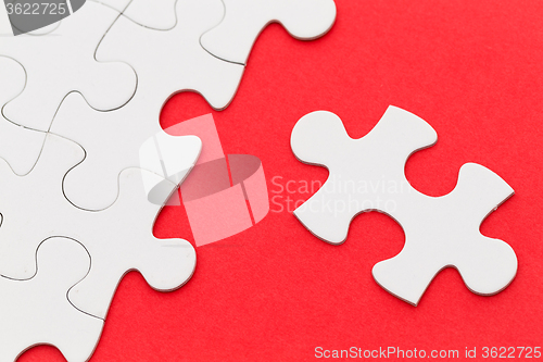 Image of Incomplete white puzzle with red color background with copyspace