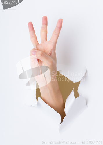 Image of Three finger breaking through paper wall