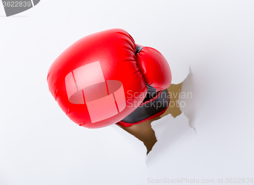 Image of Punching boxing glove though over paper wall