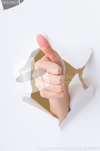 Image of Hand break through paper with thumb up gesture