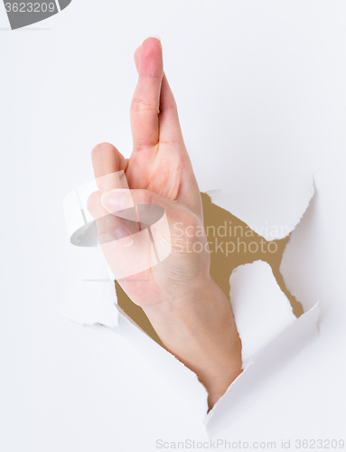 Image of Lucky sign hand gesture breaking through the paper wall