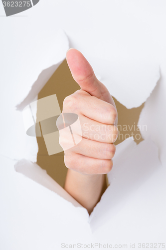 Image of Thumb up hand gesture break through the paper wall