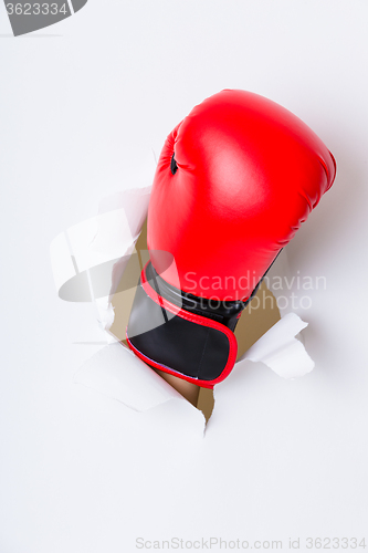 Image of Hand break through paper with red boxing gloves