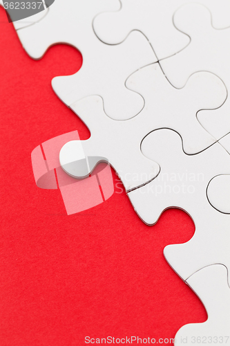 Image of Blank white jigsaw puzzles on a bright red paper background