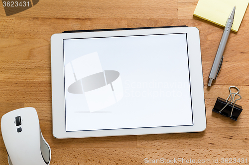 Image of Modern working desk with digital tablet presenting a blank scree