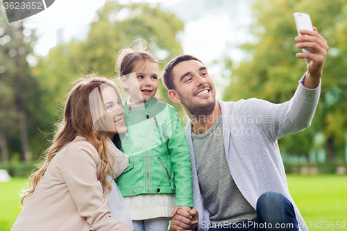 Image of happy family taking selfie by smartphone outdoors