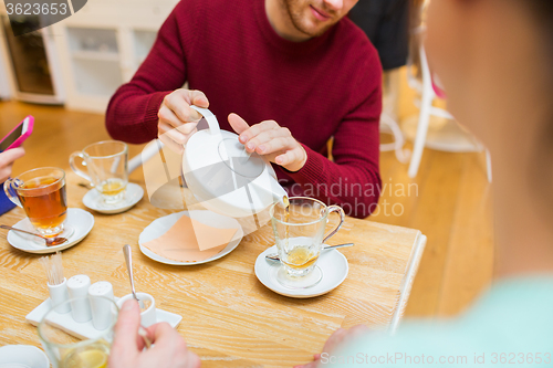 Image of close up of man with pot pouring tea at cafe