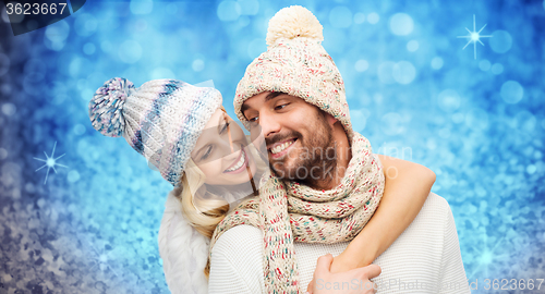 Image of happy couple in winter clothes hugging over lights