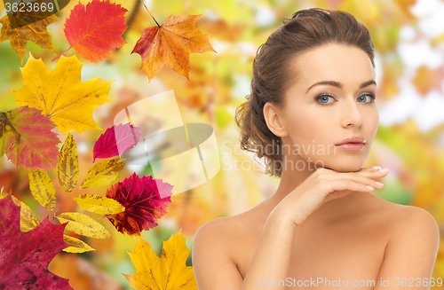 Image of beautiful woman touching her face over autumn