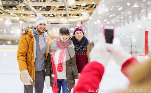 Image of happy friends taking photo on skating rink
