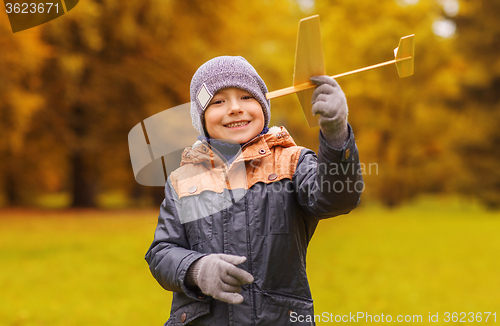 Image of happy little boy playing with toy plane outdoors