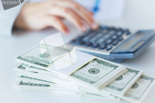 Image of close up of hand counting money with calculator