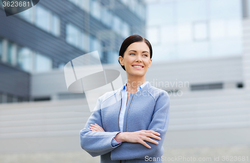 Image of young smiling businesswoman over office building