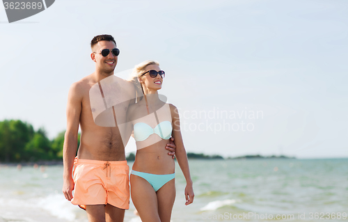 Image of happy couple in swimwear walking on summer beach