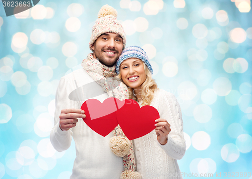 Image of smiling couple in winter clothes with red hearts