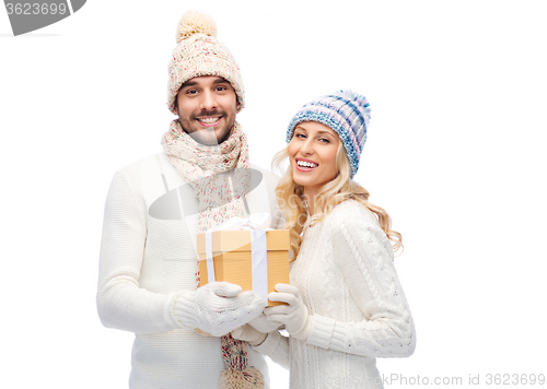 Image of smiling couple in winter clothes with gift box