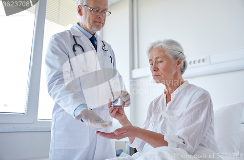 Image of doctor giving medicine to senior woman at hospital