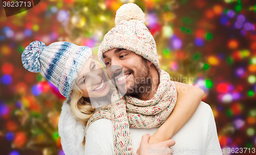 Image of happy couple in winter clothes hugging over lights