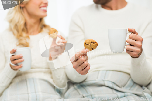 Image of close up of happy couple with cookies and tea cups