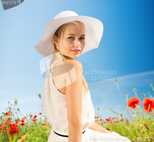 Image of smiling young woman in straw hat on poppy field