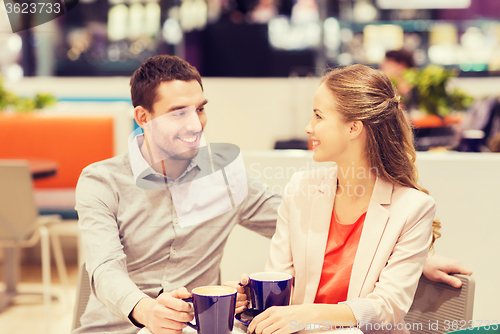 Image of happy couple with shopping bags drinking coffee