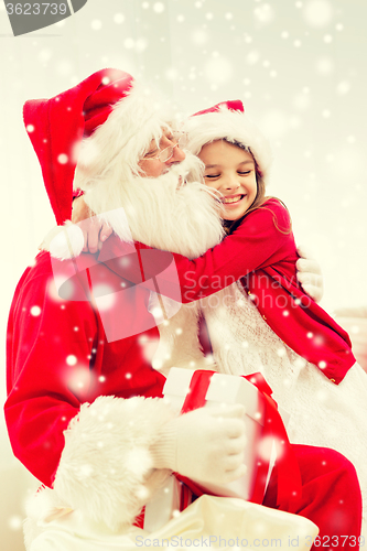 Image of smiling girl with santa claus and gift at home