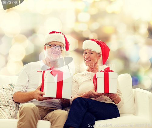 Image of happy senior couple in santa hats with gift boxes
