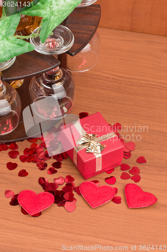 Image of glass of vine, red hearts and small present