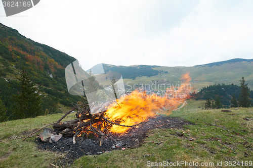 Image of hiking man prepare tasty sausages on campfire