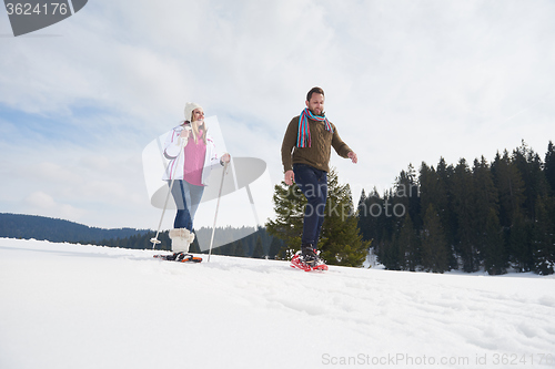 Image of couple having fun and walking in snow shoes