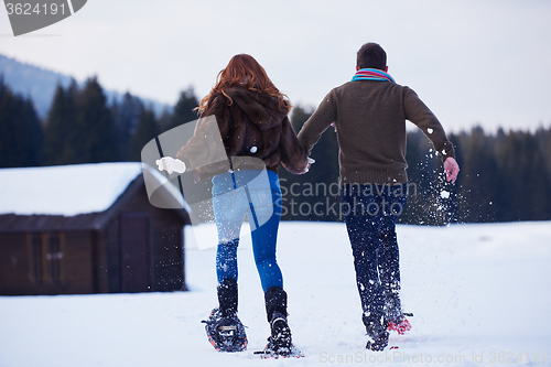 Image of couple having fun and walking in snow shoes