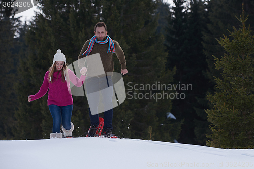 Image of couple having fun and walking in snow shoes