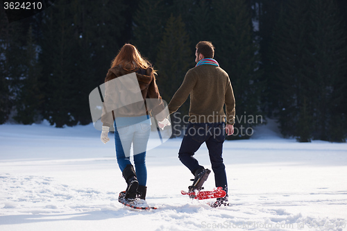 Image of couple having fun and walking in snow shoes