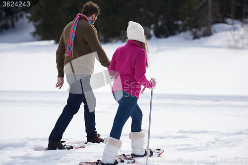 Image of couple having fun and walking in snow shoes