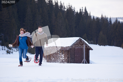 Image of couple having fun and walking in snow shoes