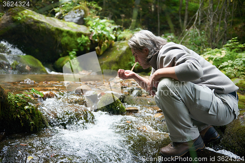 Image of man drinking fresh water from spring