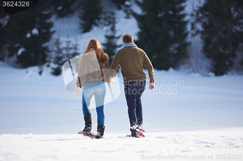 Image of couple having fun and walking in snow shoes